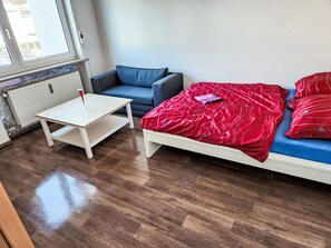 A room with a bed, a sofa, a small table, and a radiator. - Einfache 1-Zimmer Wohnung by Interhome (Bad Wörishofen)