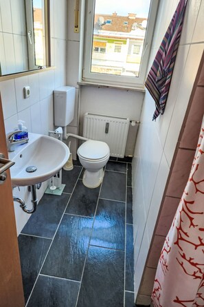 A small bathroom with a white sink, toilet, and radiator. - Einfache 1-Zimmer Wohnung by Interhome (Bad Wörishofen)