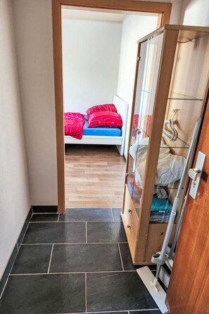 A narrow hallway leading to a bedroom with a bed, a wardrobe, and a mirror. - Einfache 1-Zimmer Wohnung by Interhome (Bad Wörishofen)
