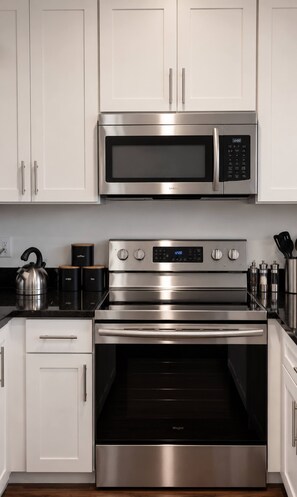 A kitchen with stainless steel appliances, including a microwave, oven, and kettle. - Sleeps 10 Near Broadway | Hart Suites Unit #2 (Nashville)