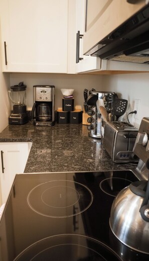 Eine Küche mit einem schwarzen Herd, einer Kaffeemaschine, einem Toaster und verschiedenen Küchenutensilien.
