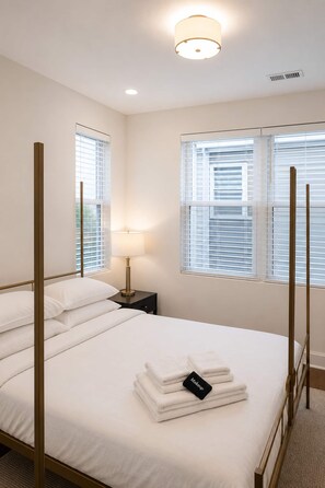 Een hotelkamer met een bed, nachtkastjes, een lamp en een raam met jaloezieën.