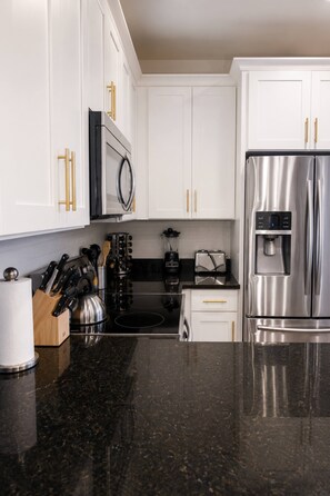 Een moderne keuken met witte kasten, roestvrijstalen apparatuur en een granieten aanrecht.