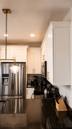 A modern kitchen with stainless steel appliances, a granite countertop, and white cabinetry. - 10 Min to Broadway | Sleeps 8 | Hart Suites #16 (Nashville)