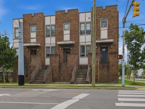 A multi-story brick building with a flat roof, a set of stairs leading to the entrance, and a pedestrian crossing in front. - Luxury 3BR Retreat | Minutes from Broadway (Nashville)