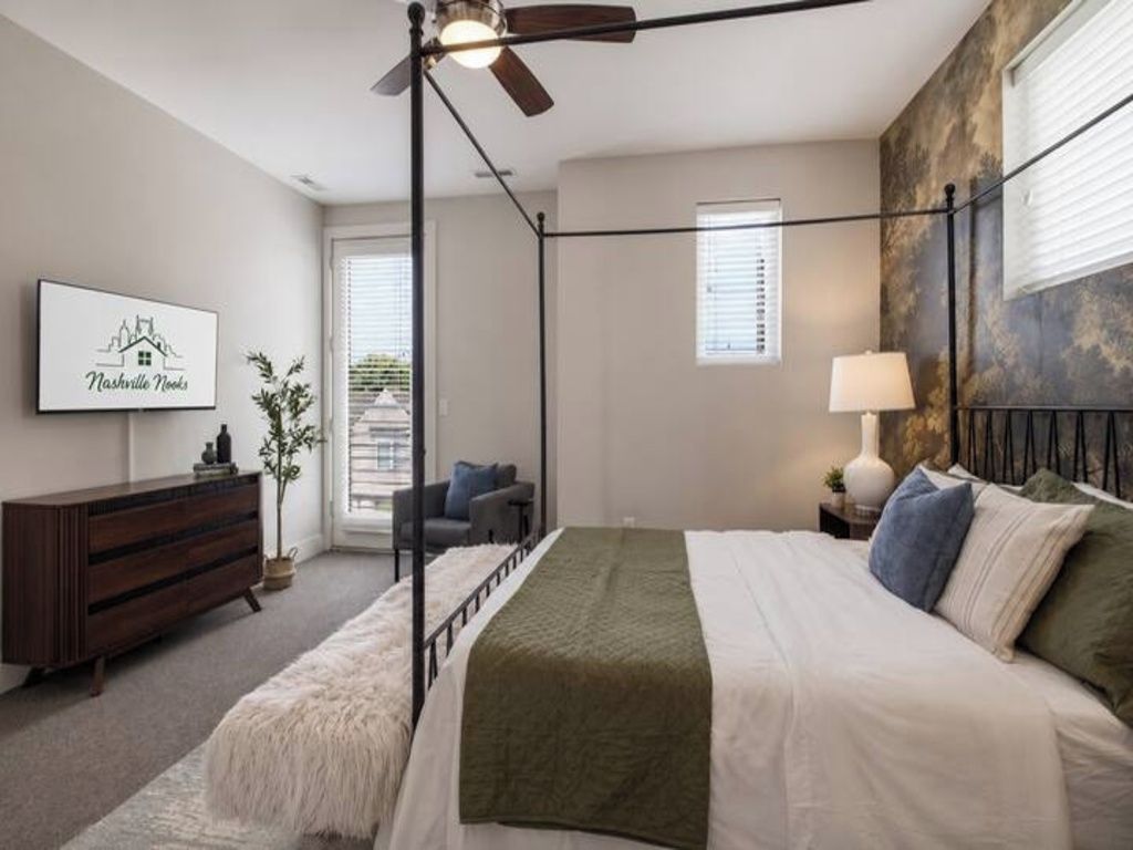 Une chambre à coucher avec un lit à baldaquin, un ventilateur de plafond, une table de chevet avec une lampe, une commode et un tableau encadré au mur.