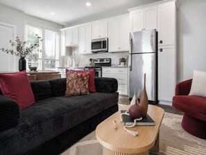 A modern living room with a dark sofa, a wooden coffee table, and a red armchair. - Luxury 3BR Retreat | Minutes from Broadway (Nashville)