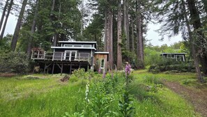 A cabin in a forest with a deck and a separate building.