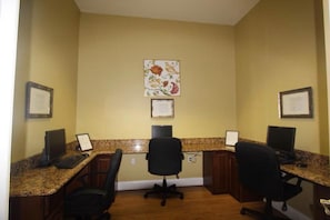 Ein Konferenzraum mit zwei Schreibtischen, jeweils ausgestattet mit einem Computer und einem Stuhl. An der Wand befinden sich gerahmte Zertifikate.