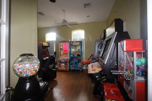 Ein Zimmer mit Spielautomaten, einem Gumball-Automaten und einem Deckenventilator.