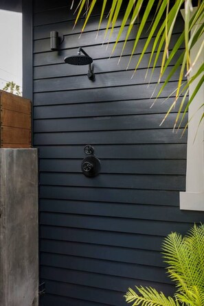 A dark-colored exterior wall with a modern outdoor shower, two control knobs, and a small window. - Luxury 1913 Craftsman in Venice Beach (Los Angeles)