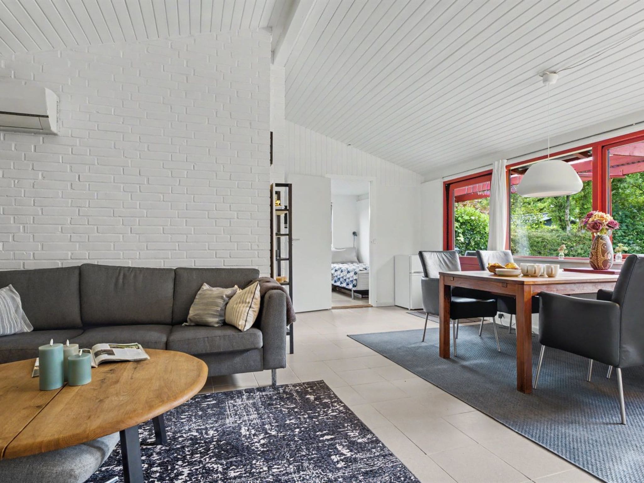 Een moderne woonkamer met een grijze bank, een salontafel, en een eethoek met een tafel en stoelen.