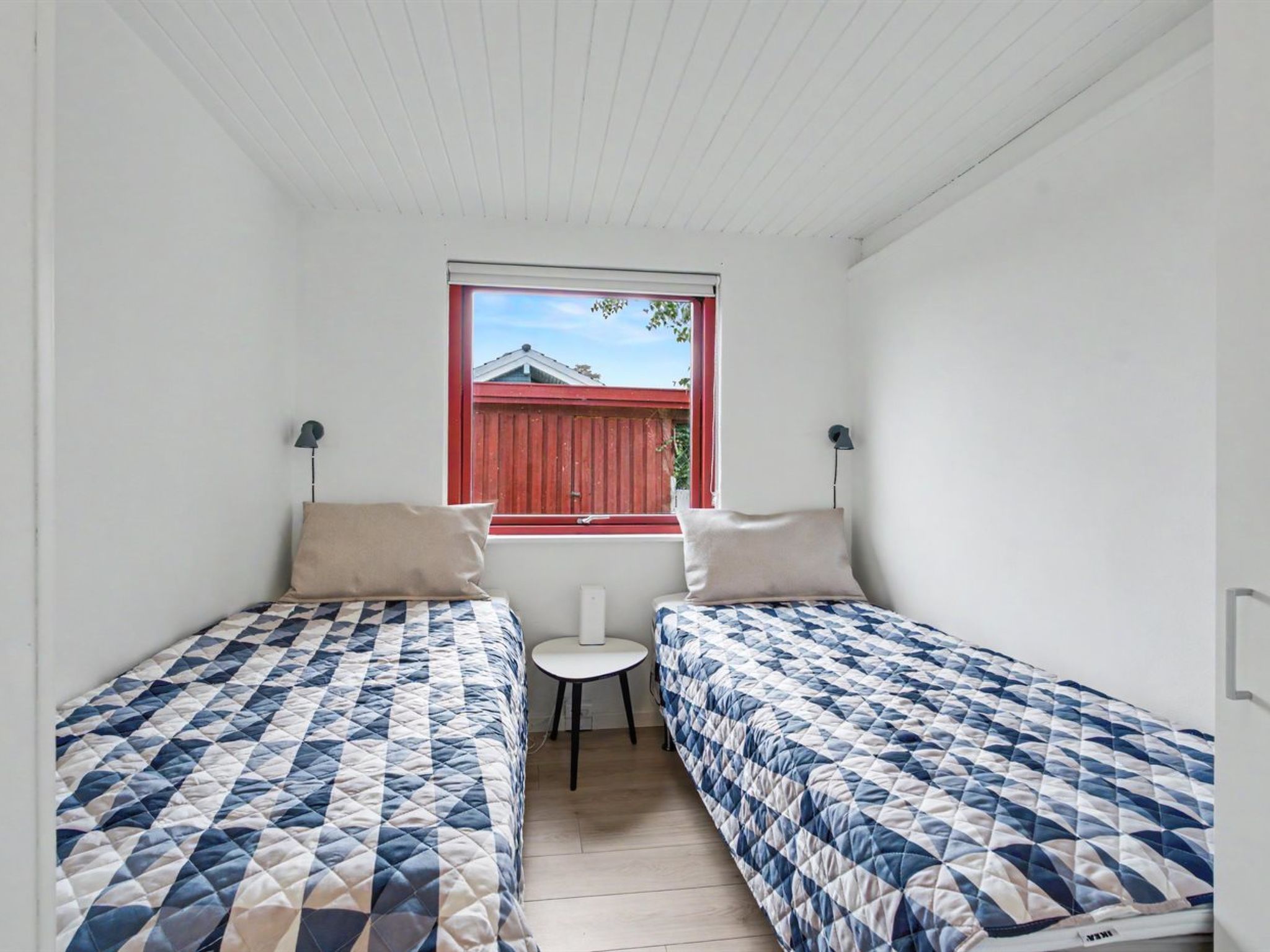 Un petit logement composé d’une seule pièce, comprenant deux lits, une fenêtre et une petite table.