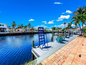 A waterfront property with a dock, a poolside area with chairs, and a clear view of the water. - Pool & Hot Tub! Waterfront+Close To Beach! (Pompano Beach)