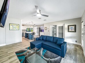 A modern living room with a sectional sofa, a glass coffee table, and a ceiling fan. - Pool & Hot Tub! Waterfront+Close To Beach! (Pompano Beach)