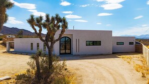 A modern house with a desert landscape, a clear sky, and mountains in the background. - Cielo Vista by Avantstay Private Pool + Heated Spa Pickleball Court Fire Pit Near the Park (Joshua Tree)