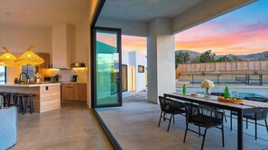 A modern kitchen with a glass door leading to a patio area with a pool. - Cielo Vista by Avantstay Private Pool + Heated Spa Pickleball Court Fire Pit Near the Park (Joshua Tree)