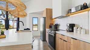 A modern kitchen with a large island, stainless steel appliances, and a view of the outdoors. - Cielo Vista by Avantstay Private Pool + Heated Spa Pickleball Court Fire Pit Near the Park (Joshua Tree)