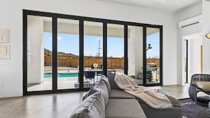 Una sala moderna con un amplio ventanal corredero que da a un patio exterior.