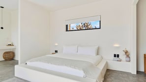 Un dormitorio moderno con una cama grande, un cuadro colgado en la pared y una mesita de noche con un jarrón.