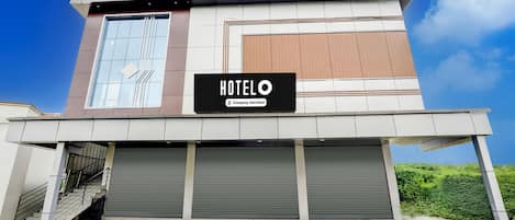 A modern hotel with a sign reading "HOTELO Company Serviced".