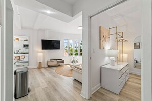Una sala moderna con una televisión de pantalla plana, un sofá, una mesa de centro y una lámpara.