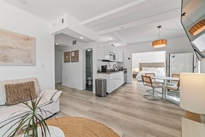 Eine moderne Wohnung mit Küche, Essbereich und Wohnzimmer mit Sofa und Pflanze.