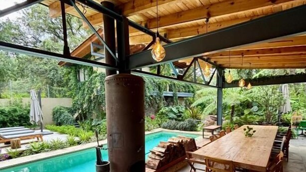 An outdoor seating area with a pool, wooden furniture, and a view of the surrounding greenery. - Pandurata Bed & Breakfast (Valle de Bravo)