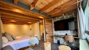 A cozy room with a bed, a stone fireplace, and a television. - Pandurata Bed & Breakfast (Valle de Bravo)