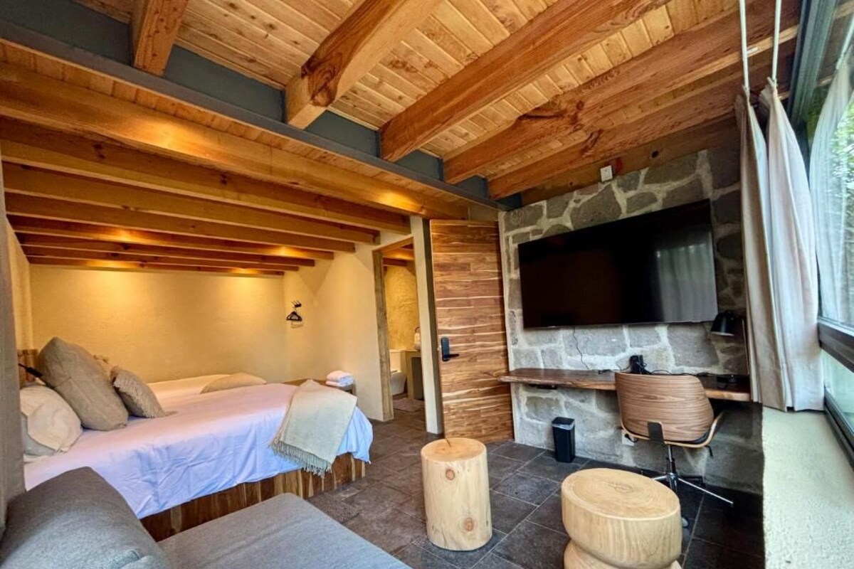 A cozy room with a bed, a stone fireplace, and a television.