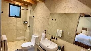 Un baño moderno con ducha, inodoro, lavamanos y un espejo grande.