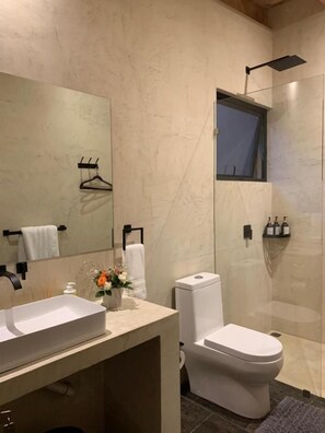 Ein modernes Badezimmer mit großem Spiegel, Toilette und Duschbereich.