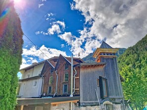 A traditional wooden building with a steep roof, a satellite dish, and a stone entrance.