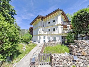 Un edifici de diverses plantes amb façana de pedra, un balcó i una escala que condueix a l'entrada.