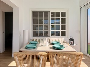 A dining area with a table set for four, featuring woven chairs and a large window with multiple panes. - CANARY LIGHT MASPALOMAS (Maspalomas)