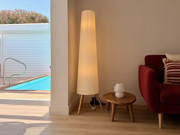 Een kamer met een zwembad, een hoge vloerlamp, een rode bank en een klein houten tafeltje.