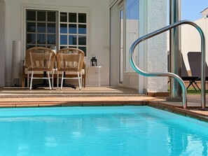 A swimming pool with a metal handrail, two wicker chairs, and a table with a lamp. - CANARY LIGHT MASPALOMAS (Maspalomas)