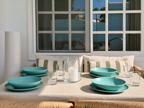Een eethoek met een tafel voor vier personen, met blauwgroene borden en glazen.