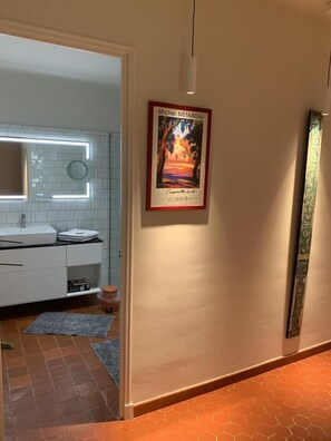 A hallway with a framed artwork on the wall, a white bathroom with a modern sink and mirror, and a tiled floor. - G3334 - DRAGUIGNAN - City Break (DRAGUIGNAN)
