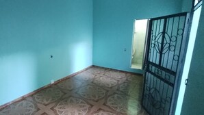 Una habitación con paredes verde mar, piso estampado y una reja de metal.