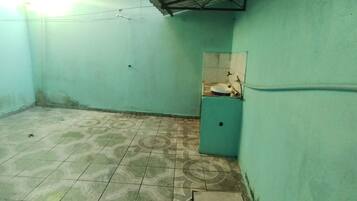 A small, enclosed bathroom with a toilet, a sink, and a tiled floor.
