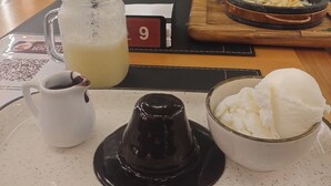 Una mesa con una bandeja que contiene un vaso de té helado, una jarra pequeña de café y un tazón de helado.