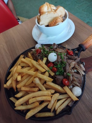 A meal consisting of steak, fries, and bread on a table. - Vrbo Property (Manaus)