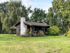A rustic cabin with a chimney, surrounded by a grassy yard and trees. - 5 Person Holiday Home in Rockneby (Rockneby)