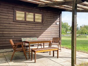 A wooden outdoor patio with a table and chairs, a cushioned bench, and a pergola overhead. - 5 Person Holiday Home in Rockneby (Rockneby)