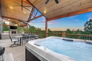 A hot tub on a wooden deck with a view of the landscape. - New! Cave Table Road! Fun Views! Hot Tub! Firepit! (Broken Bow)