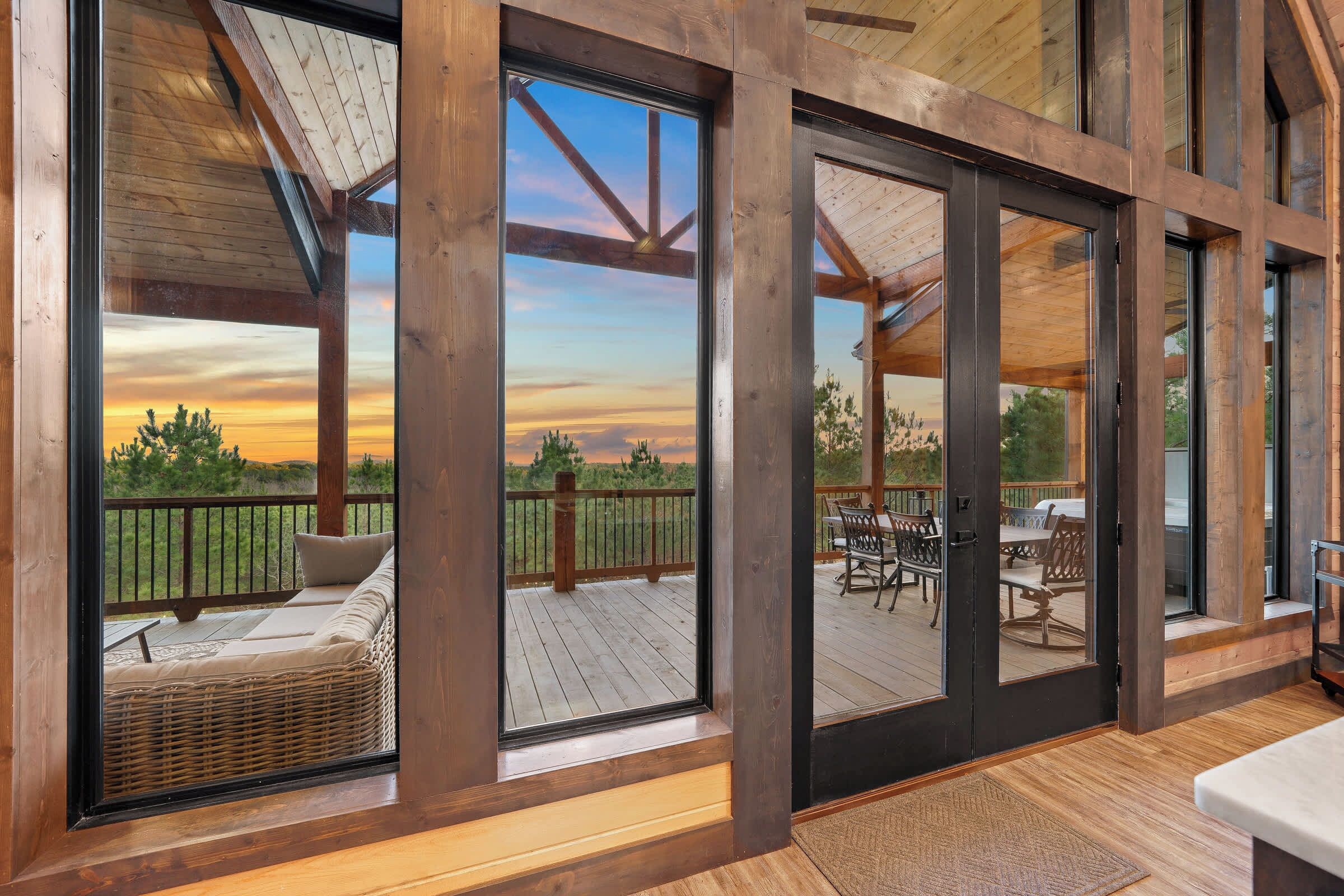 Eine Holzterrasse mit Gartenmöbeln und Blick auf einen Sonnenuntergang.