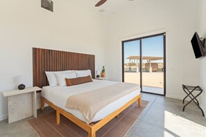 Ein Schlafzimmer mit einem Bett, einem Nachttisch, einem Fernseher und Blick ins Freie.