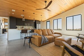 Un salon moderne comprenant un canapé, une table basse et un coin repas avec des chaises.
