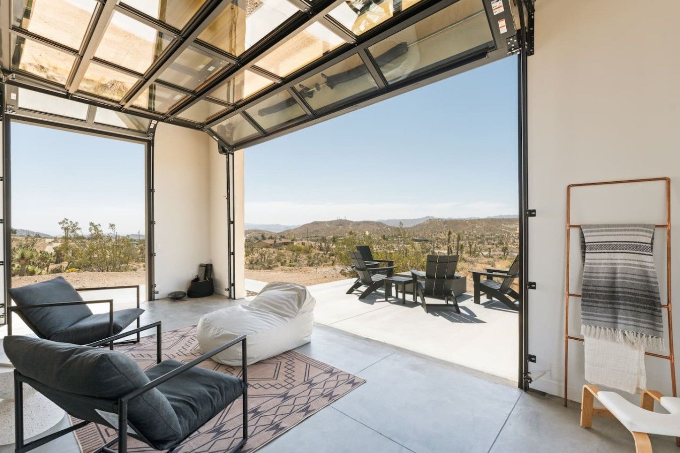A spacious room with a large glass door leading to an outdoor patio with a view of a desert landscape.